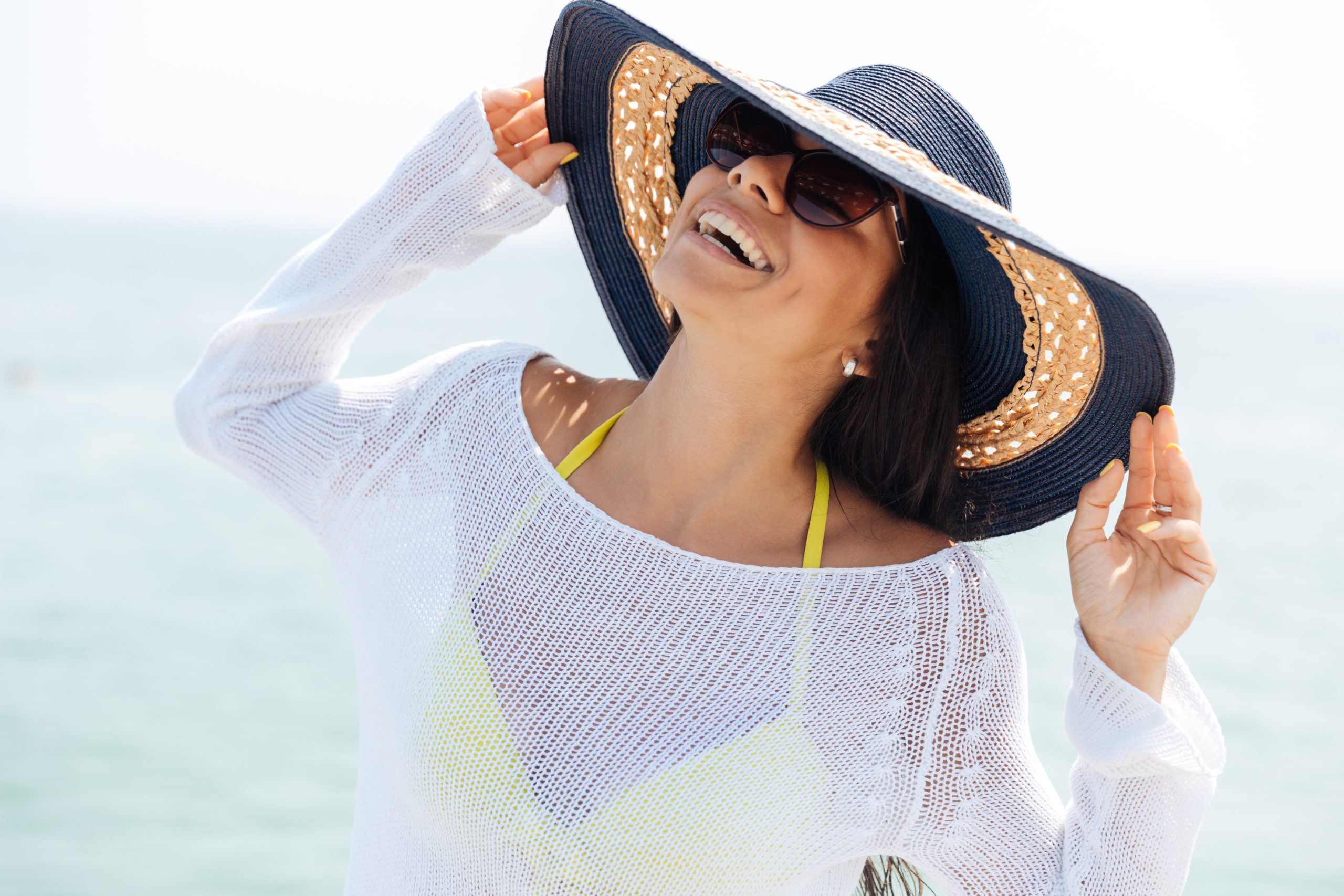 Portrait of a laughing woman wearing beach hat and bikini
